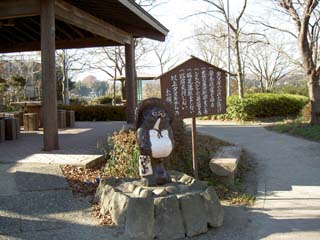 立札には「タヌキのお告げ」が書かれている。 タヌキの置物